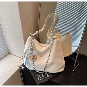 Detail view of white hobo bag with metal chain strap and cute bear plush charm