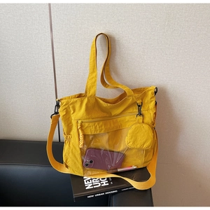 Detail of mustard yellow nylon tote bag featuring a transparent pocket and coin purse