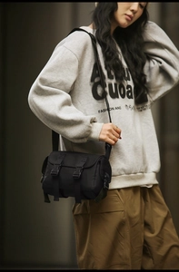 Detail of durable black nylon messenger bag with buckle closures and side pocket