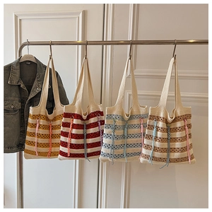 Detail of colorful knitted crochet tote bags with striped patterns and tassel charms