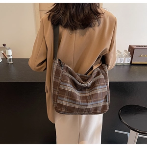 Borsa hobo vintage a quadri marroni con tracolla larga indossata da una modella