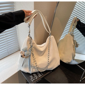 Detailed macro view of white textured leather Hobo tote bag with blue bear charm