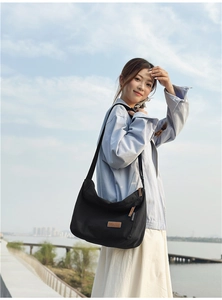 Close-up of black water-resistant nylon messenger bag with brown leather brand tag