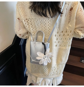 Détail du sac seau métallisé argenté avec fleur en maille blanche et logo FUOR