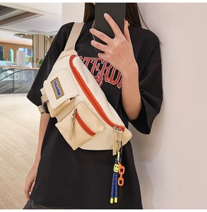 Détail du sac de poitrine en toile avec fermeture éclair orange et chaîne décorative en acrylique