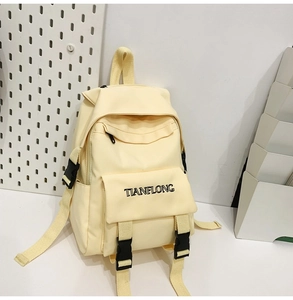 Detail of light yellow canvas backpack with TIANFLONG logo and black buckle straps