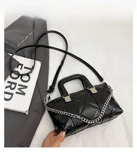Close-up of black quilted leather handbag with silver chain detail on white fabric
