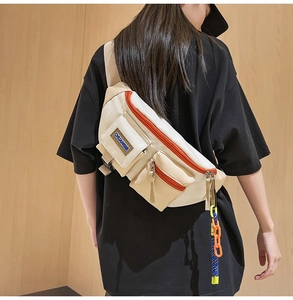 Détail du sac bandoulière en toile beige avec zips orange et poches multiples