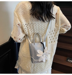 Détail d'un mini sac seau argenté avec breloque fleur blanche 3D et fine bandoulière