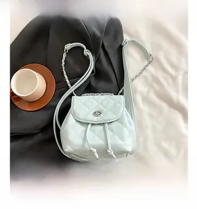 Detail view of light blue quilted mini backpack with chain strap and silver twist lock