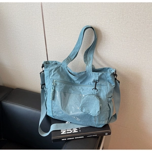 Detail of light blue nylon tote bag with adjustable strap and round mini coin purse