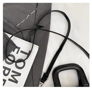 Detail of glossy black quilted pillow bag showing silver hardware and detachable strap