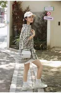 Outdoor shot of a stylish white nylon crossbody bag and checkered shirt on a model