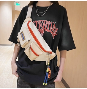 Détail du sac de poitrine en toile blanc cassé avec zip orange et breloque sourire