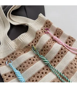 Detail of bohemian knitted tote with hollow crochet stripes and colorful rope charms