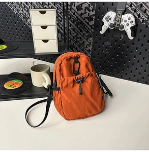 Détail du sac bandoulière orange en nylon imperméable avec poche à cordon et mousqueton