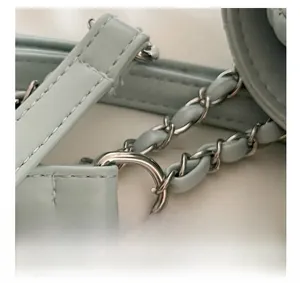 Detail of mint green quilted leather strap with woven silver metal chain and hardware