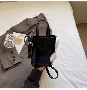 Détail du mini sac seau noir avec breloque fleurie et bandoulière réglable
