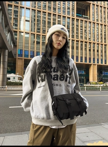 Street style shot of a black nylon messenger bag with buckle closure and wide strap
