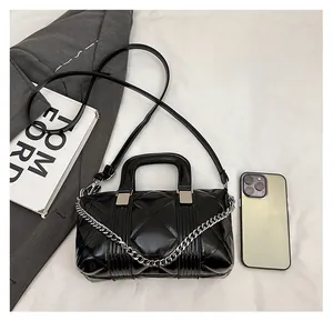Flat lay of black quilted pillow bag with silver chain and size reference items