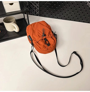 Vue détaillée du sac bandoulière orange imperméable avec cordon et mousqueton noir