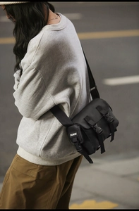 Detail view of black messenger bag with double buckles and adjustable fabric strap