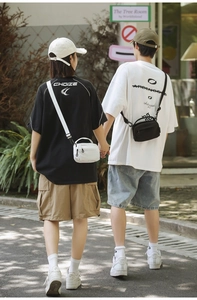 Outdoor view of couple wearing minimalist black and white crossbody bags with grid texture