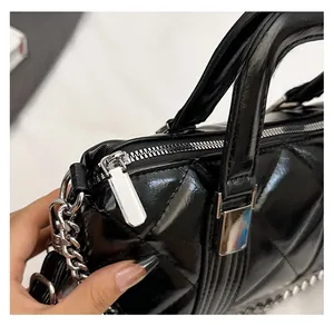 Detail of silver smooth zipper and quilted glossy black leather on the handbag side