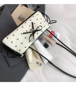Detail shot of cream shoulder bag with bow, heart pendant, and spacious interior items
