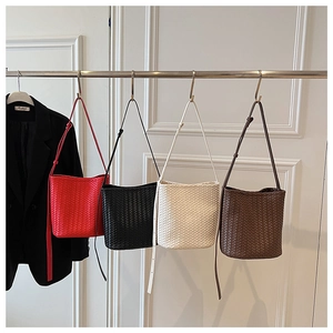 Série de sacs seaux tissés en rouge, noir, beige et marron sur un support en métal