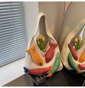 Detailed mesh view of a woven tote bag featuring colorful stuffed fish charms and wide straps