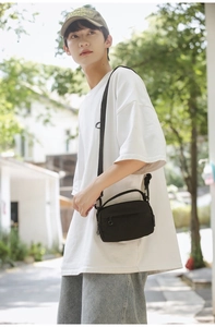 Outdoor shot of a black minimalist crossbody bag with adjustable strap and zipper pocket