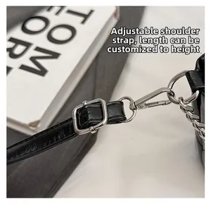 Detail of adjustable black leather shoulder strap with silver metal buckle and spring hook