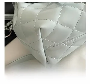 Detailed view of precision stitching on light blue quilted leather backpack with chain strap