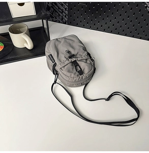 Détail de la sacoche bandoulière en nylon gris imperméable avec étiquette de la marque
