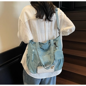 Detail showing light blue nylon tote bag with transparent phone pocket and mini pouch