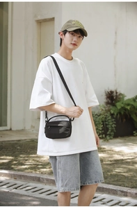 Detail shot of the black nylon crossbody bag featuring the top handle and adjustable strap