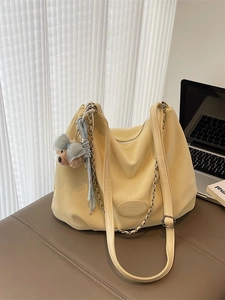 Minimalist light yellow tote bag with chain strap and cute bear charm in a home office