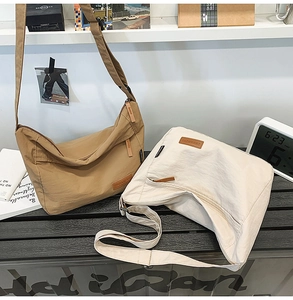 Detail of adjustable straps and nylon texture on large khaki and beige messenger bags