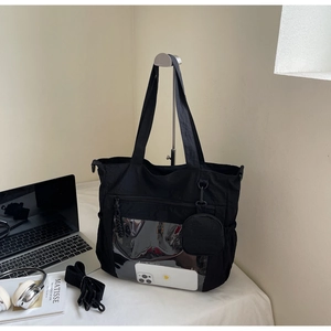 Macro view of black nylon tote bag with transparent PVC window and round pouch accessory