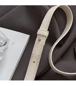 Detailed close-up of cream leather strap with silver metal adjustment stud and stitching