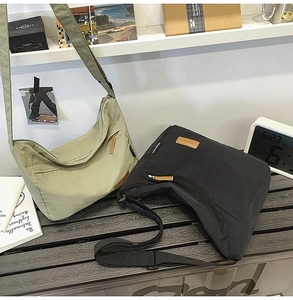 Waterproof nylon messenger bags in olive green and black on a wooden bench