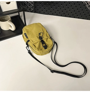 Détail macro du sac bandoulière en nylon imperméable jaune moutarde avec cordon élastique