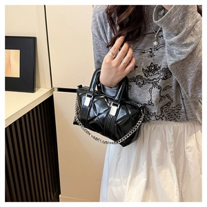Chic black quilted crossbody bag with silver chain strap shown on a model in a casual setting