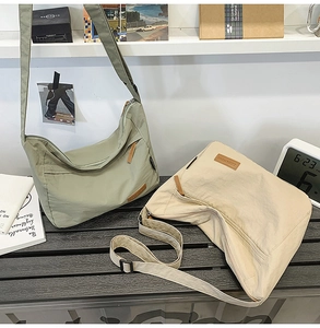 Detail view of large nylon messenger bags in green and cream with adjustable straps