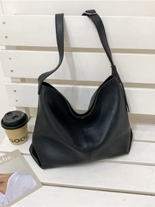 Retro black leather tote bag with large capacity and adjustable strap on a bench