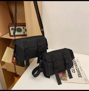 Detail showing two sizes of black nylon messenger bags with adjustable straps