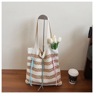 Close-up of striped knit tote bag featuring colorful braided ropes and floral accents
