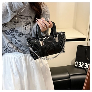 Fashionable black quilted glossy handbag with silver chain strap shown in a lifestyle setting