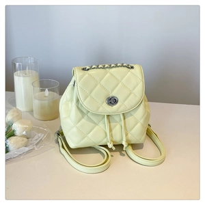 Detail of cream yellow quilted backpack featuring a silver turn-lock and chain strap